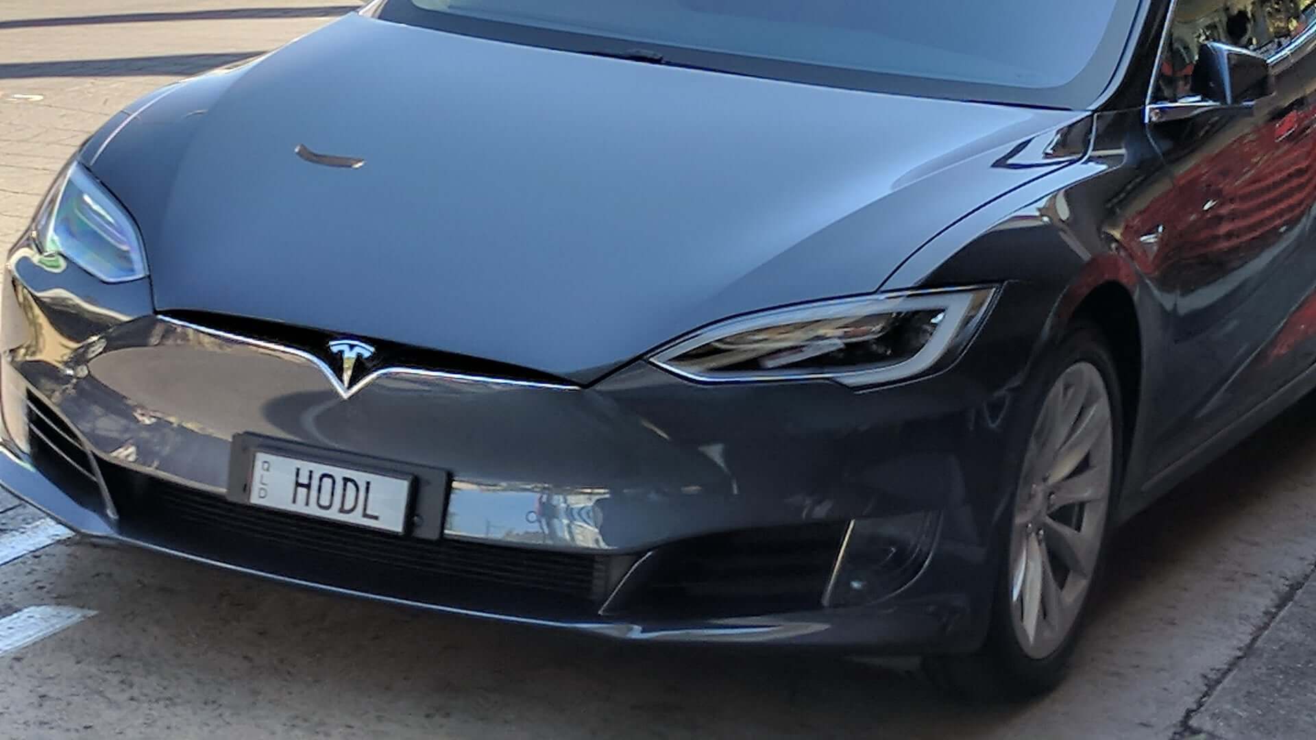 Крупная транзакция с биткоинами в 2025 году. Tesla с криптовалютным номером, призывающим хранить биткоины. Фото.